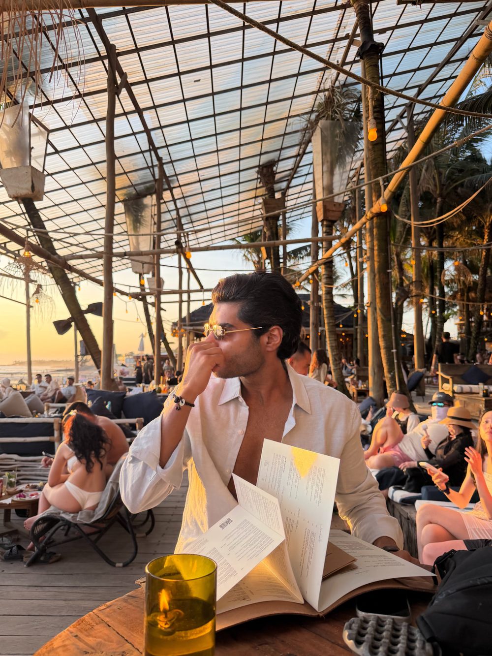 Man in sunglasses at a beach club table during sunset